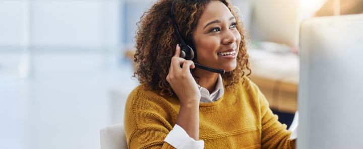 Afbeelding van een doktersassistente die aan de telefoon zit voor haar computerscherm
