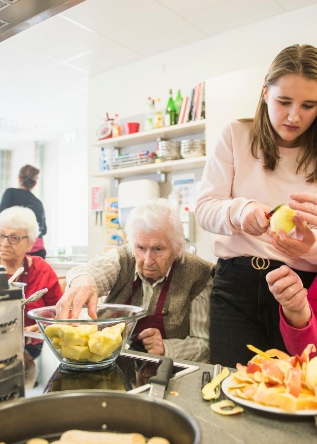 afbeelding van een groep mensen met psychosociale problemen die eten aan het voorbereiden zijn.