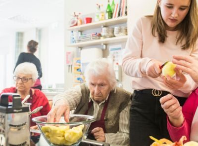 afbeelding van een groep mensen met psychosociale problemen die eten aan het voorbereiden zijn.