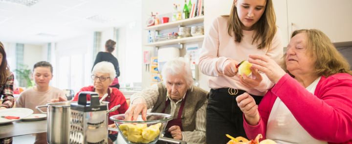 afbeelding van een groep mensen met psychosociale problemen die eten aan het voorbereiden zijn.