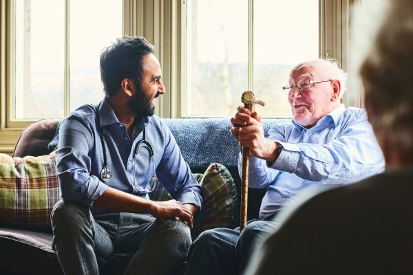 Afbeelding van een zorprofessional die in gesprek is met een ouder iemand.